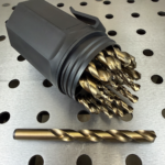 M42 cobalt jobber drill bits in black index case on perforated steel workbench, with one drill bit displayed in front showing 135-degree split point and gold oxide finish.