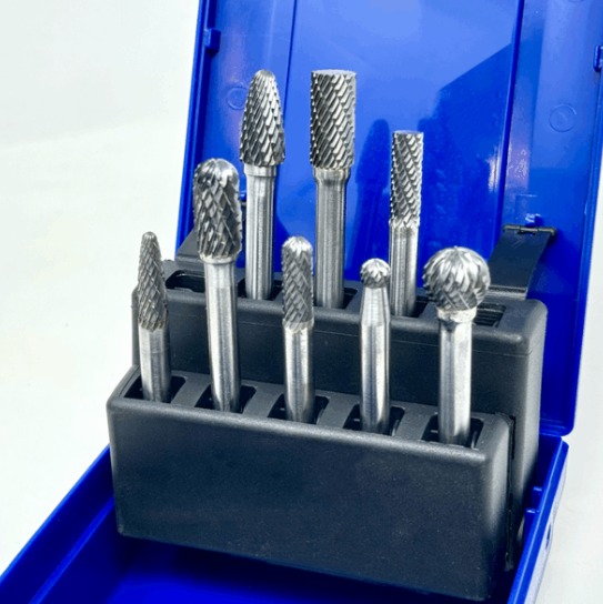 Open blue case contains a set of metal rotary burr bits with cylindrical, pointed, rounded, and tapered cutting heads.