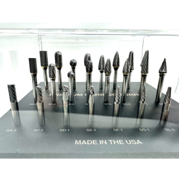 A collection of metal carbide rotary burr bits in various shapes displayed on a black stand labeled "Made in the USA."