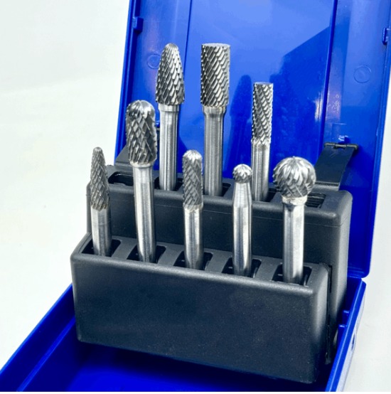 Eight silver carbide rotary burr bits with textured cutting heads arranged in a black holder inside an open blue case.